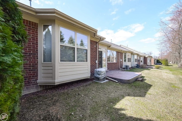 back of house featuring a yard, brick siding, a patio area, and central AC unit