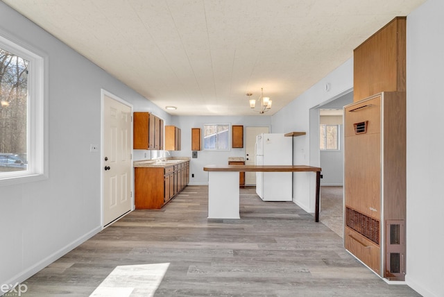 2407 Karen St, Prescott, MI 48756 - kitchen featuring freestanding refrigerator, light wood-type flooring, a chandelier, a sink, and brown cabinets