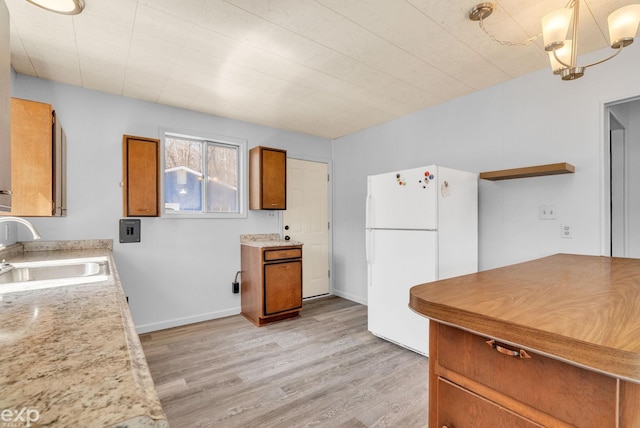 2407 Karen St, Prescott, MI 48756 - kitchen with freestanding refrigerator, brown cabinetry, a sink, light countertops, and light wood finished floors