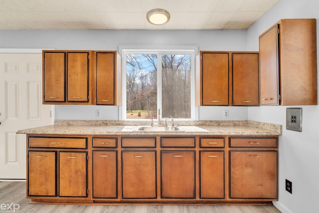 2407 Karen St, Prescott, MI 48756 - kitchen with brown cabinetry, a sink, and light wood-style flooring