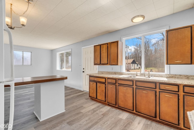 2407 Karen St, Prescott, MI 48756 - kitchen featuring light wood-style floors, freestanding refrigerator, brown cabinetry, a sink, and light countertops