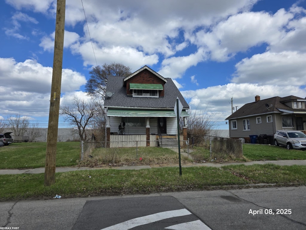 bungalow featuring roof with shingles, a fenced front yard, and a front yard