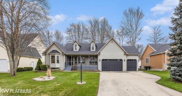 view of front of property featuring an attached garage, concrete driveway, a front yard, and a porch