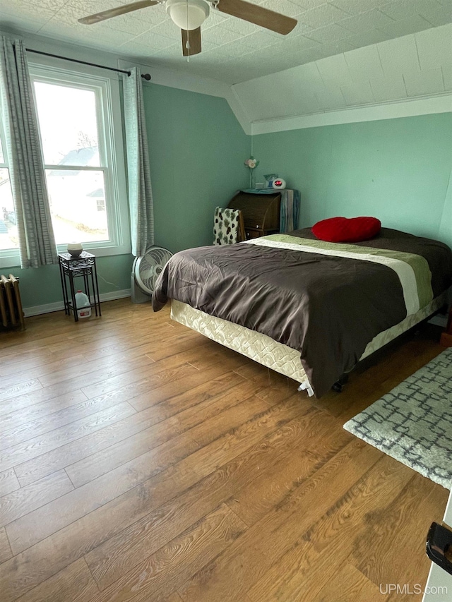 1215 Dakota Ave, Gladstone, MI 49837 - bedroom featuring lofted ceiling, wood finished floors, radiator, baseboards, and a ceiling fan