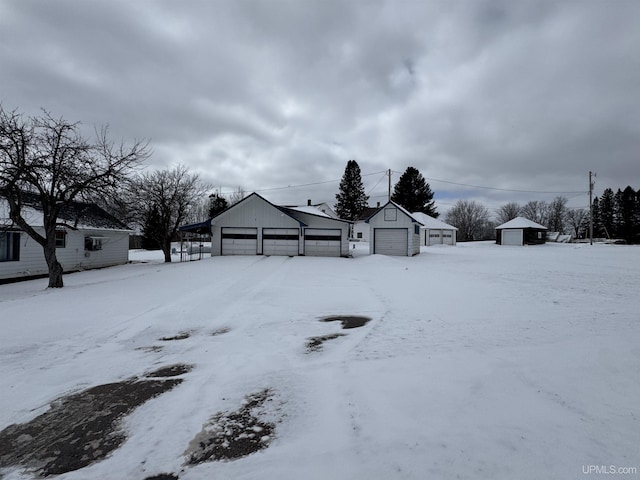 yard covered in snow featuring a detached garage and an outdoor structure