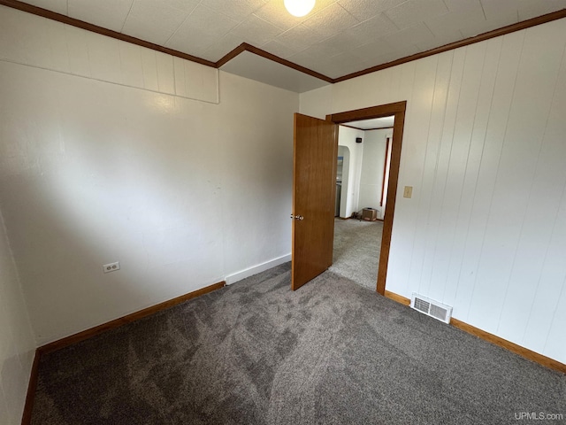 carpeted spare room featuring ornamental molding, arched walkways, and visible vents
