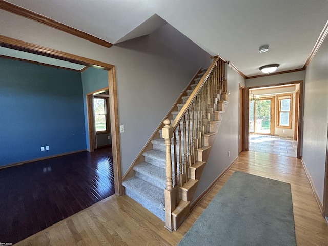 staircase featuring crown molding, baseboards, and wood finished floors