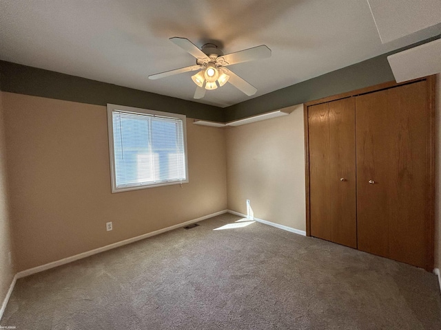 unfurnished bedroom featuring a closet, baseboards, visible vents, ceiling fan, and carpet