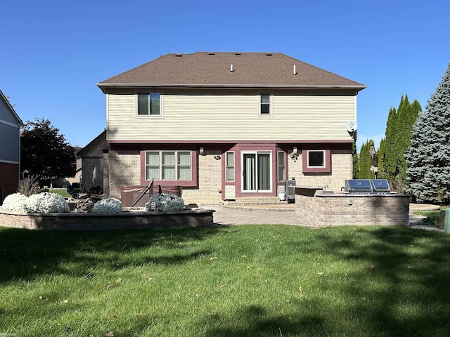 rear view of property featuring brick siding, a patio area, a lawn, and an outdoor kitchen
