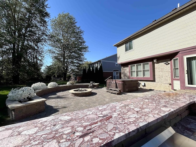 view of patio / terrace with an outdoor fire pit and a hot tub