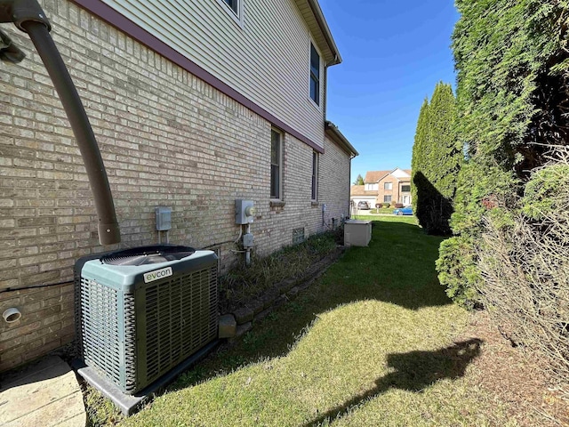 view of side of home with crawl space, a lawn, brick siding, and central AC