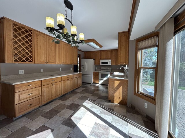kitchen with white appliances, a chandelier, light countertops, a sink, and hanging light fixtures