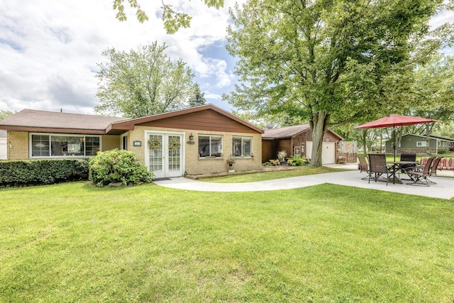 rear view of property featuring a patio, french doors, a lawn, and brick siding