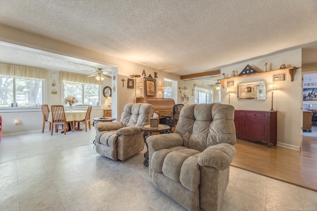living area with baseboards, a ceiling fan, and a textured ceiling
