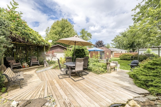 wooden terrace with an outbuilding, fence, and outdoor dining area