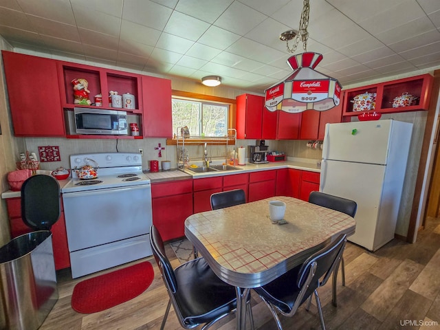 kitchen with light wood-style floors, white appliances, open shelves, a sink, and red cabinetry