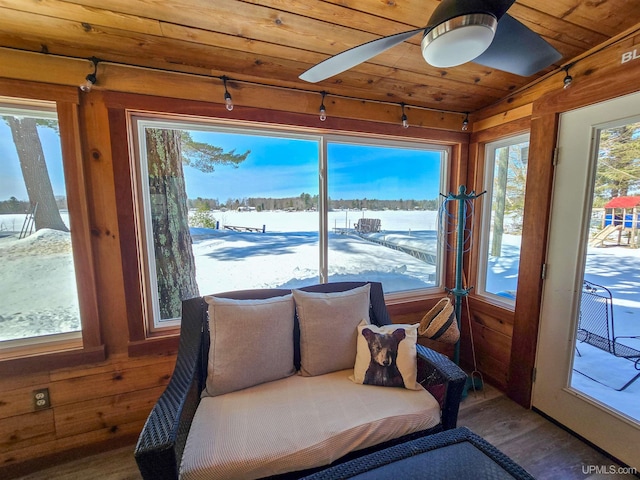 sunroom / solarium with a water view, wooden walls, wood ceiling, and wood finished floors