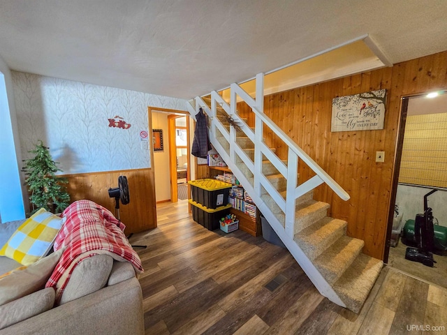 stairs featuring wood finished floors and wood walls