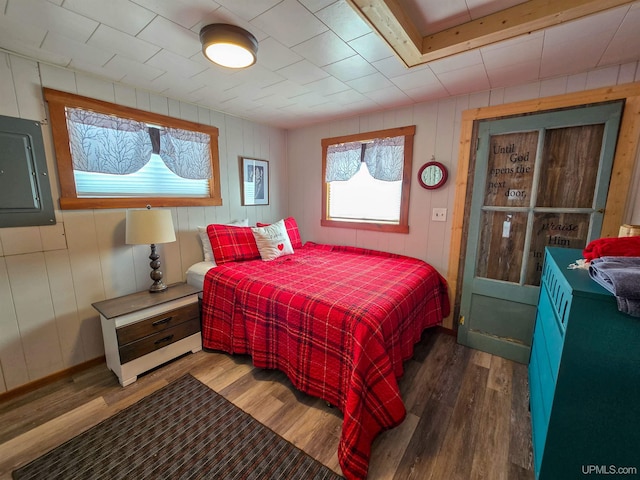 bedroom with wood walls, multiple windows, and wood finished floors