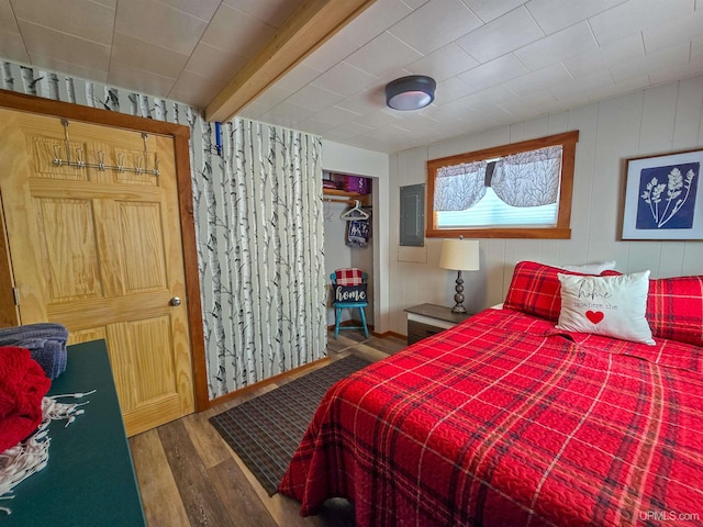 bedroom with a closet, wood finished floors, and electric panel