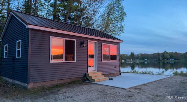 view of front of home featuring a patio, entry steps, a water view, a standing seam roof, and metal roof