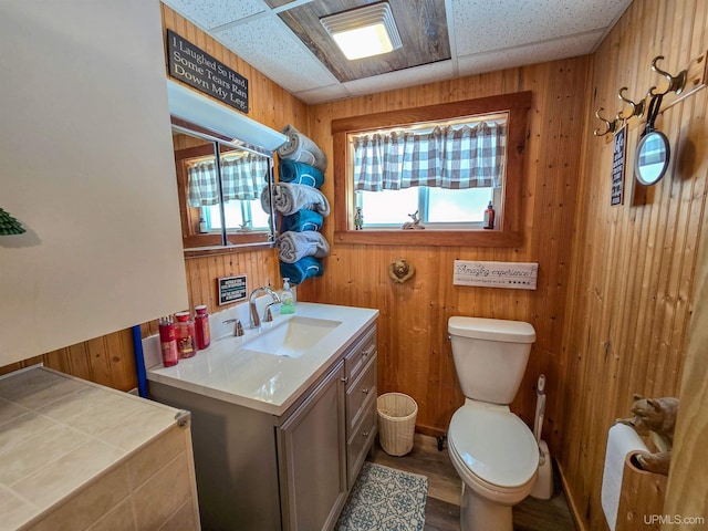 bathroom featuring wood walls, vanity, toilet, and wood finished floors