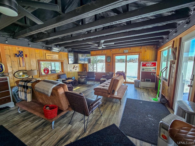 living room featuring wood walls, rail lighting, wood finished floors, and beamed ceiling