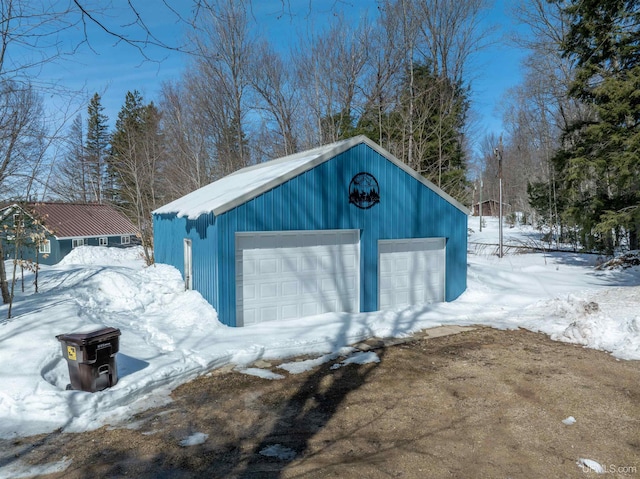 snow covered structure with an outbuilding