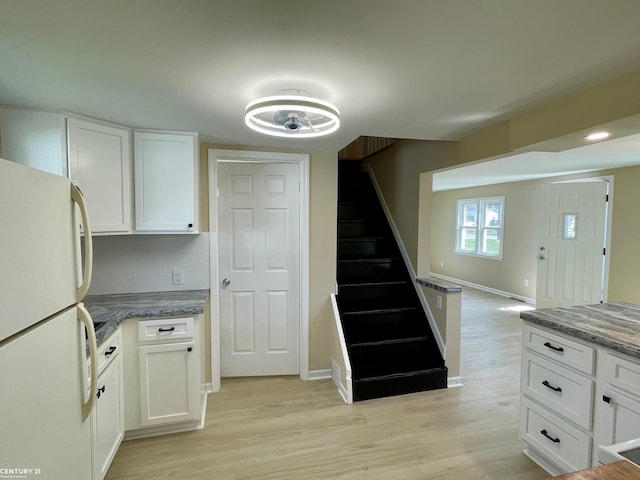 kitchen with white cabinets, light wood-type flooring, freestanding refrigerator, and baseboards