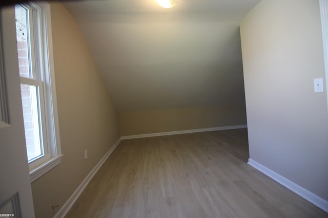additional living space with wood finished floors, baseboards, and vaulted ceiling