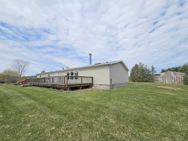rear view of property featuring crawl space, a deck, and a lawn
