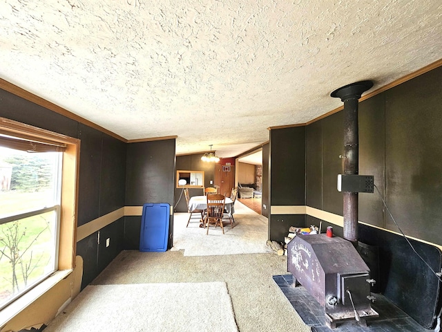 living room featuring a textured ceiling, a wood stove, crown molding, and carpet floors