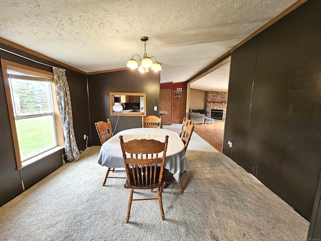 dining space featuring an inviting chandelier, a fireplace, crown molding, a textured ceiling, and carpet flooring
