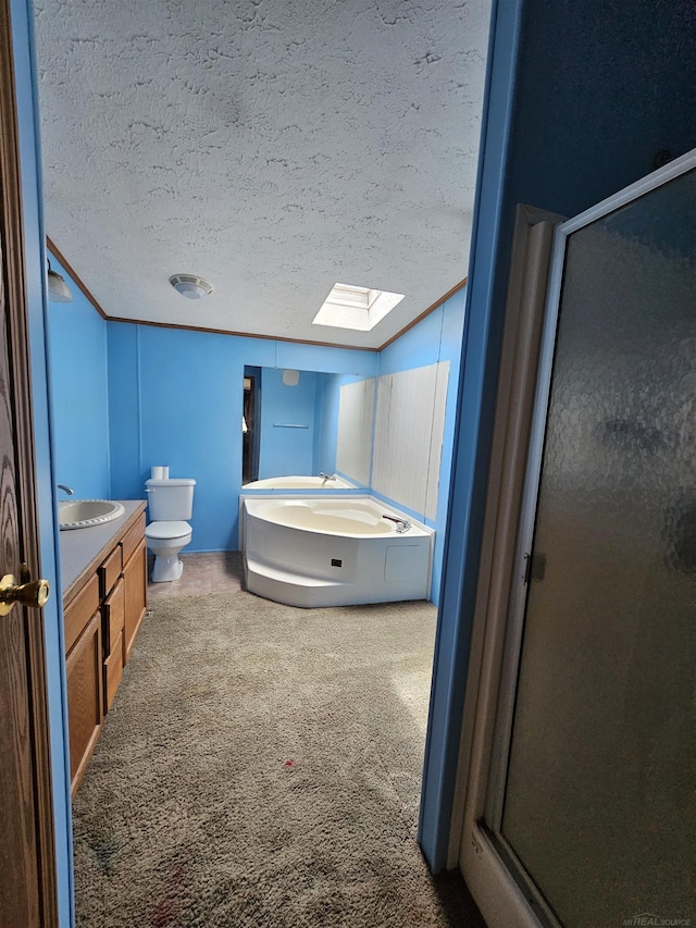 bathroom with a textured ceiling, vanity, toilet, a skylight, and a stall shower