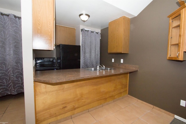 kitchen with a sink, tile patterned floors, black appliances, and a peninsula