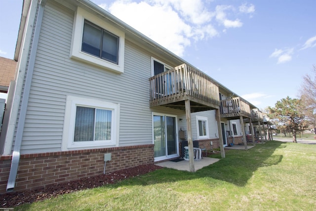 back of property featuring brick siding, a patio area, and a lawn