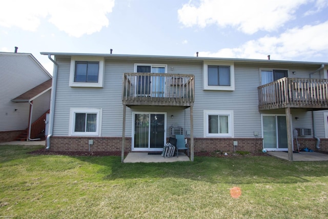 back of property featuring brick siding, a patio, and a lawn