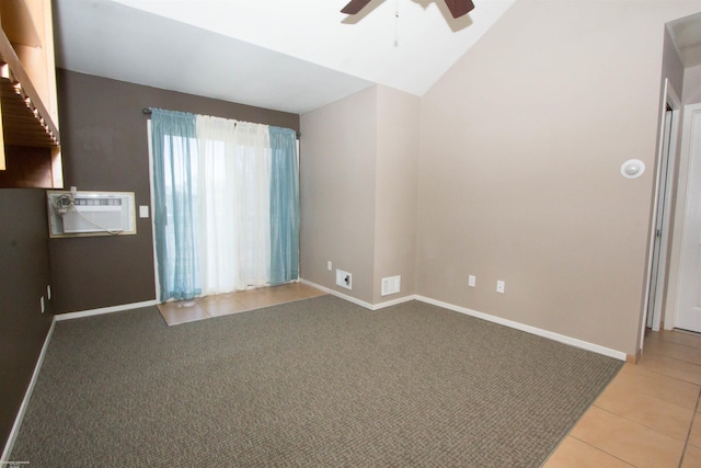 spare room featuring baseboards, vaulted ceiling, a wall mounted air conditioner, a ceiling fan, and light tile patterned flooring