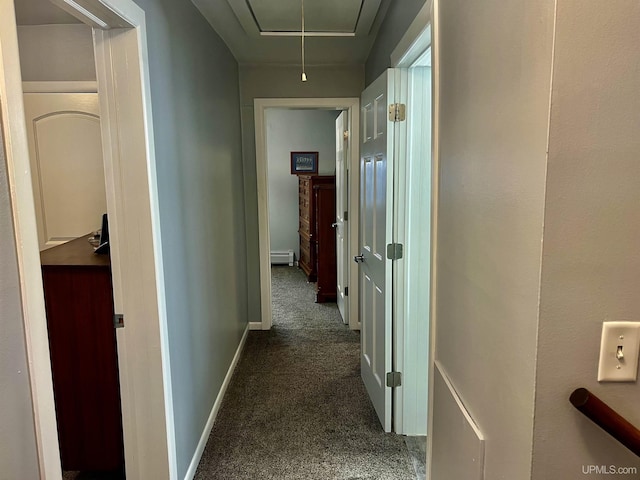 hallway with baseboard heating, attic access, dark colored carpet, and baseboards