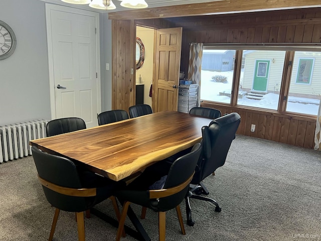 dining space featuring a healthy amount of sunlight, radiator heating unit, wooden walls, and carpet