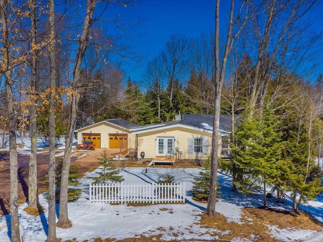 view of front of property featuring french doors, driveway, and a fenced front yard