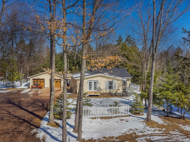 view of front facade featuring french doors, a fenced front yard, a detached garage, and driveway