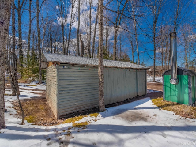 snow covered structure featuring an outbuilding and a storage unit