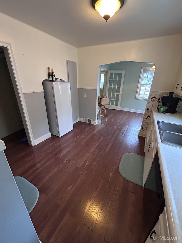 dining space with arched walkways, baseboards, dark wood finished floors, and visible vents