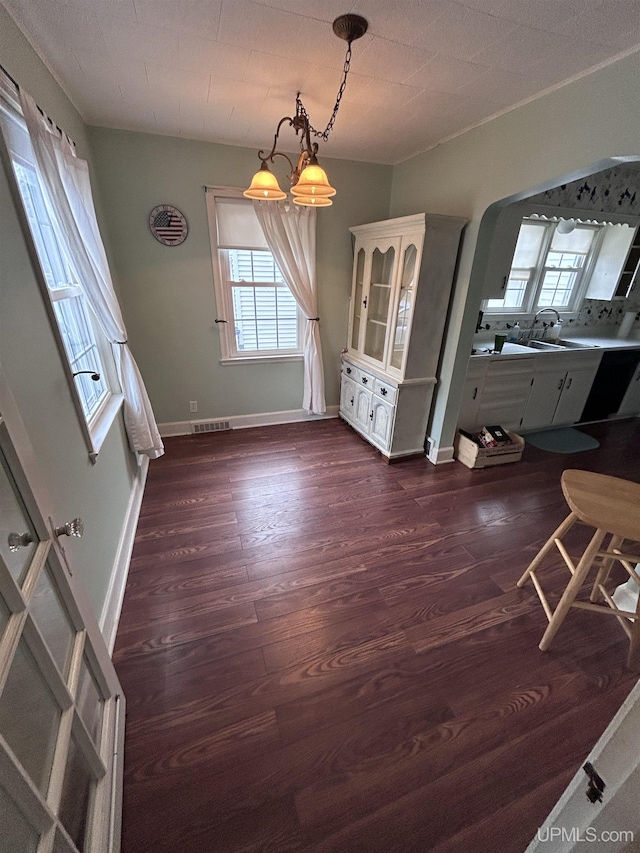 unfurnished dining area with dark wood-type flooring, baseboards, visible vents, and a wealth of natural light