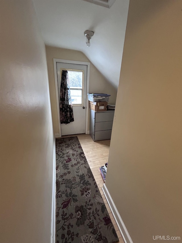 additional living space featuring baseboards, light wood-style floors, and vaulted ceiling