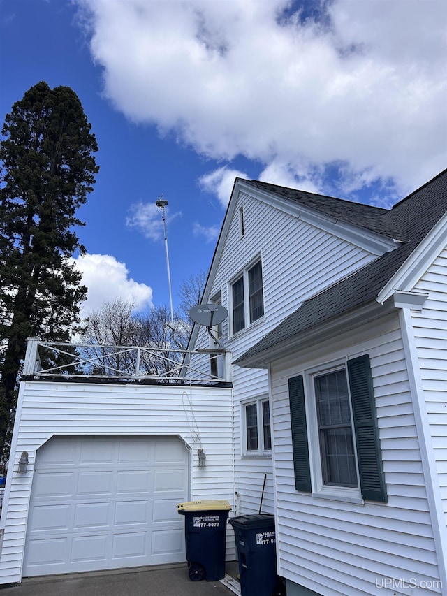 view of side of property featuring a garage and roof with shingles