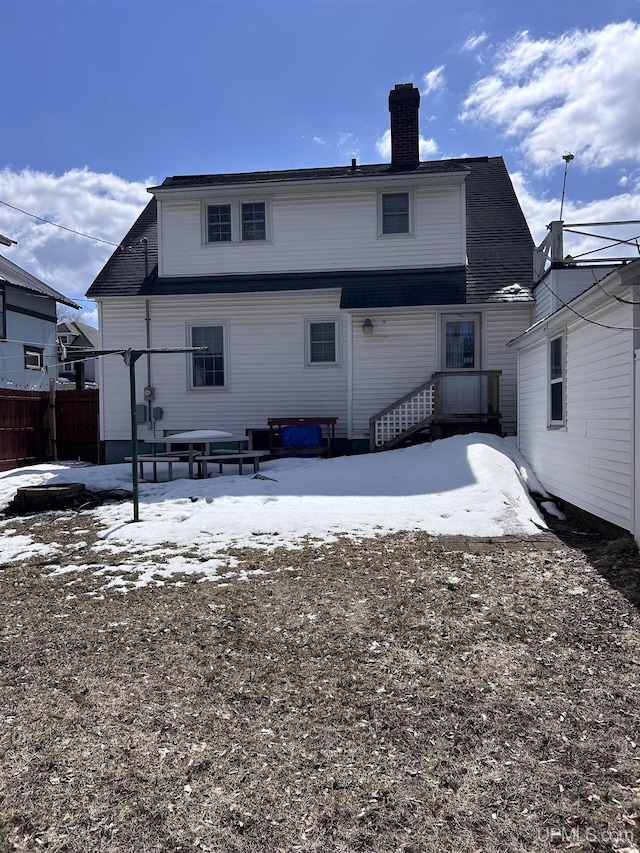 snow covered house with fence and a chimney