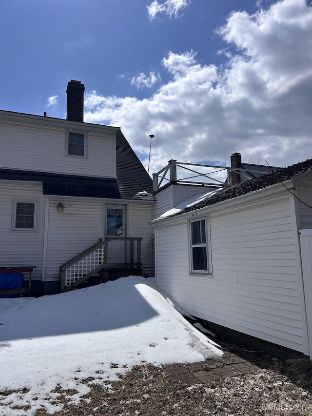 snow covered property featuring a chimney