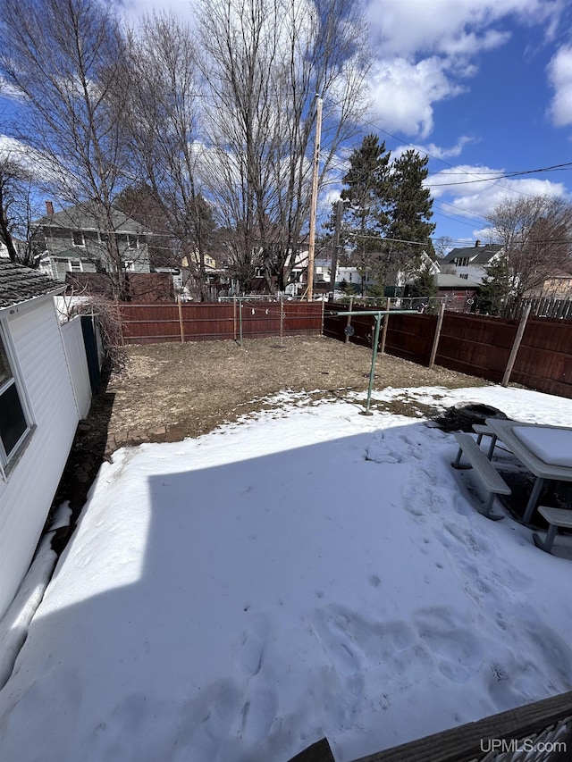 yard layered in snow with a fenced backyard